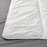 Close-up of STJÄRNBRÄCKA duvet, smooth fabric texture visible, brand label in corner.