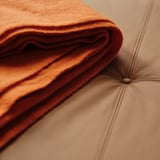 Close-up of high-quality leather bench. Soft, folded leather showcasing fine craftsmanship next to smooth, stitched upholstery.