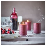 Cozy dinner setup with red candles, fruit-topped cake, and dishes.