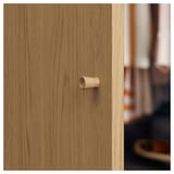 A close-up of a STORKLINTA wooden door handle on an oak-patterned door.
