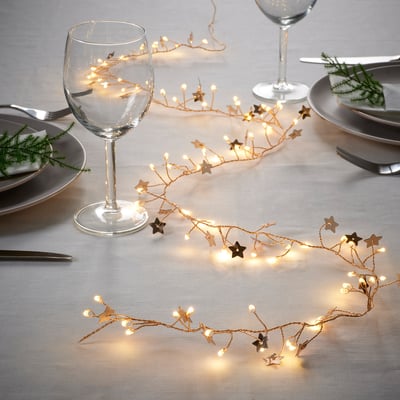 Decorative table lighting with star and berry designs, emitting a warm white glow, perfect for holiday ambiance. Runs on batteries for easy placement.
