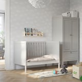 Baby nursery with light grey walls, white SUNDVIK crib, grey wardrobe, book shelf, and plush rug with toys.