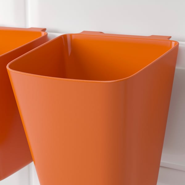 Bright orange plastic storage bins, clean and sturdy, mounted on a white wall, ideal for organizing items.