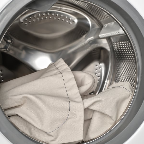 Washing machine drum with large, light-colored garment being cleaned.