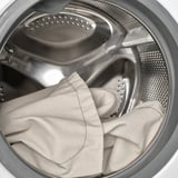Washing machine drum with large, light-colored garment being cleaned.