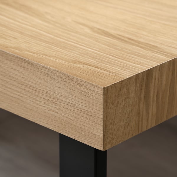 Close-up of a wooden coffee table edge with smooth, light-colored oak veneer finish.