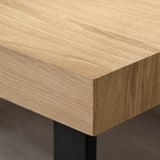 Close-up of a wooden coffee table edge with smooth, light-colored oak veneer finish.