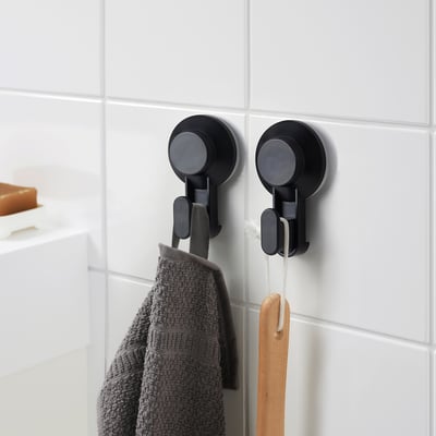 Two TISKEN hooks on tiled wall hold towel and spatula.
