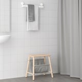 Wooden bath stool with gray TISKEN bag, perfect for bathroom storage.