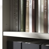 Books on white modern shelves, minimalist and organized.