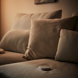 A brown couch with pillows and a remote on it.