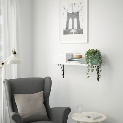 Cozy nook with chair, small table, and wall shelf with decorations and plant.
