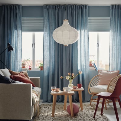 Cozy living room with large windows, TREDANSEN blinds, grey curtains, beige sofa, pendant lamp.