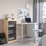 TROFAST pine storage with baskets beside desk, laptop, books. Clock on wall, grey curtain, chair. Highlights storage size.