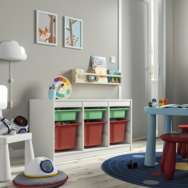 White TROFAST storage unit with green and red bins, in kids room. Provides ample storage and displays toys neatly.