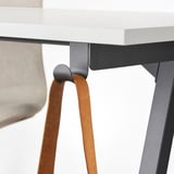 A close-up of a TROTTEN desk. It highlights the leather straps attached to its metal legs, ensuring stability and style.