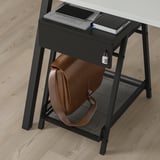 Black metal desk storage with locked drawer and brown bag beneath.