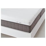 Close-up of a high-quality mattress with a white, quilted top and dark grey sides. Memory foam visible, promising comfort and support.