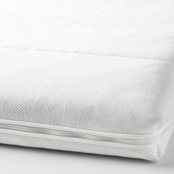 Close-up of a soft, white mattress pad with a textured surface, zipper, and smooth edges.