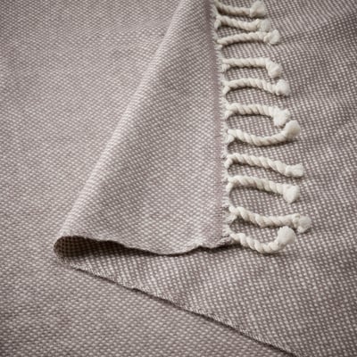 A grey wool throw blanket with fringe edges, soft and warm.