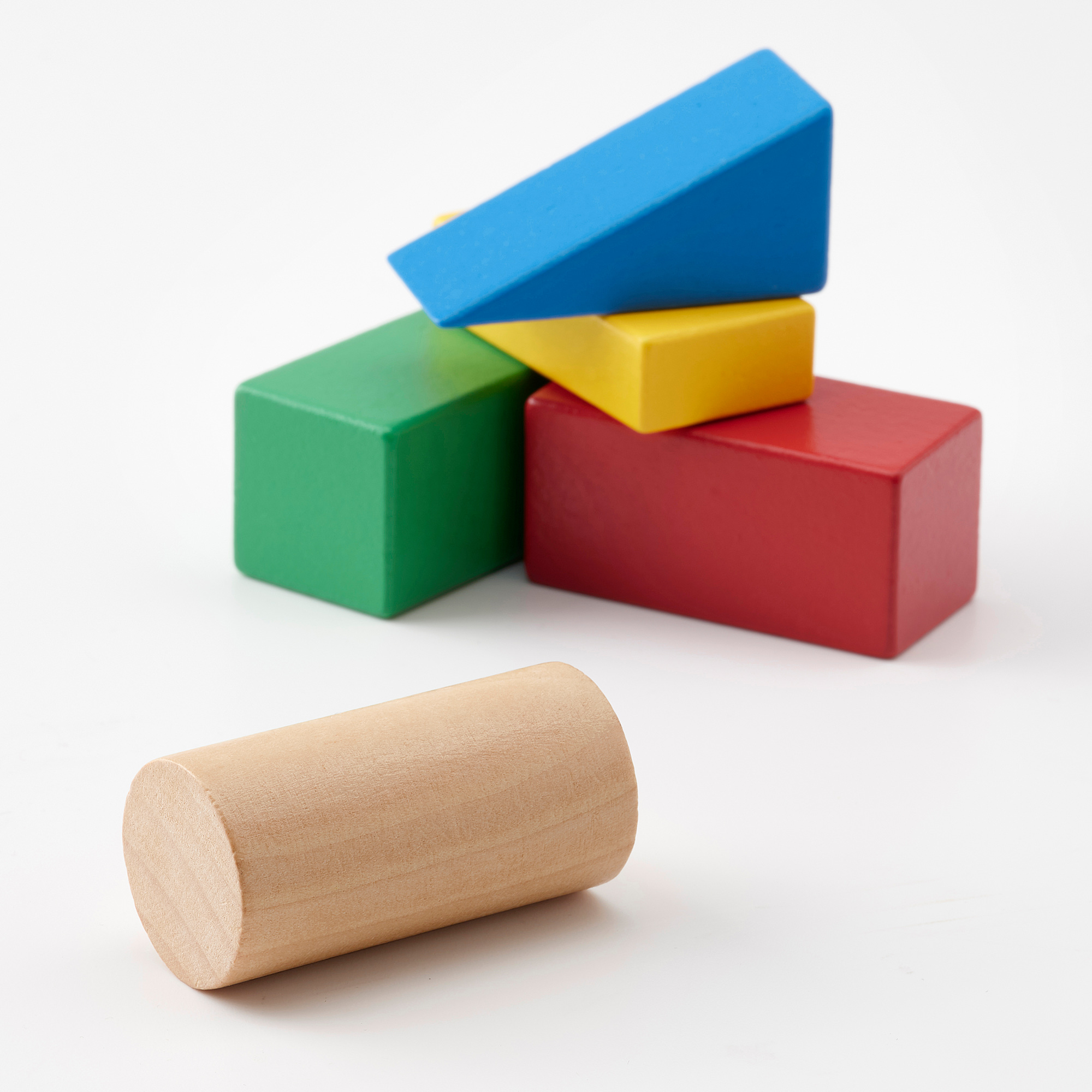 Stacked blue, yellow, green, red blocks. Brown cylinder in front.