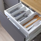 Open drawer organizer in kitchen with cutlery and utensils neatly arranged.
