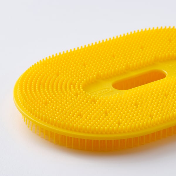 Bright yellow vegetable brush with textured surface, designed for scrubbing roots. Soft, flexible bristles for gentle cleaning.