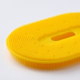 Bright yellow vegetable brush with textured surface, designed for scrubbing roots. Soft, flexible bristles for gentle cleaning.