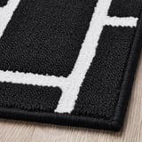 Black and white patterned rug. Textured, high-quality material on wooden floor.