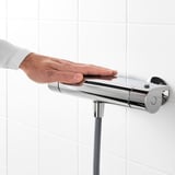 In a hand adjusts a thermostatic shower mixer. The mixer a 38°c safety stop, ensuring water doesnt get too hot.