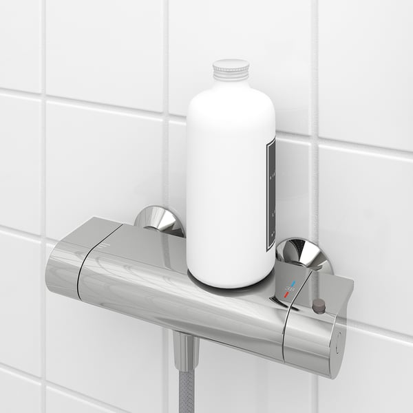 It shows a thermostatic shower mixer with a safety stop at 38°c. A bottle rests on its built-in shelf.