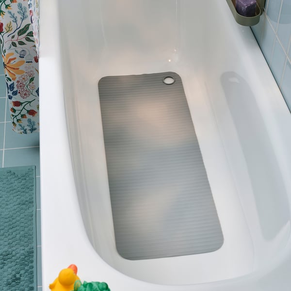 A white bathtub with a blue textured mat, a gray non-slip mat, and floral shower curtain.
