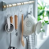 Kitchen tools on hooks: colander, opener, spoons, spatula.