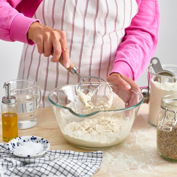 Person mixing dough with danish whisk.