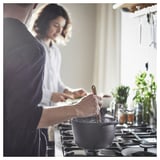 Two people cook together using VARDAGEN cast iron pots in a warm kitchen.