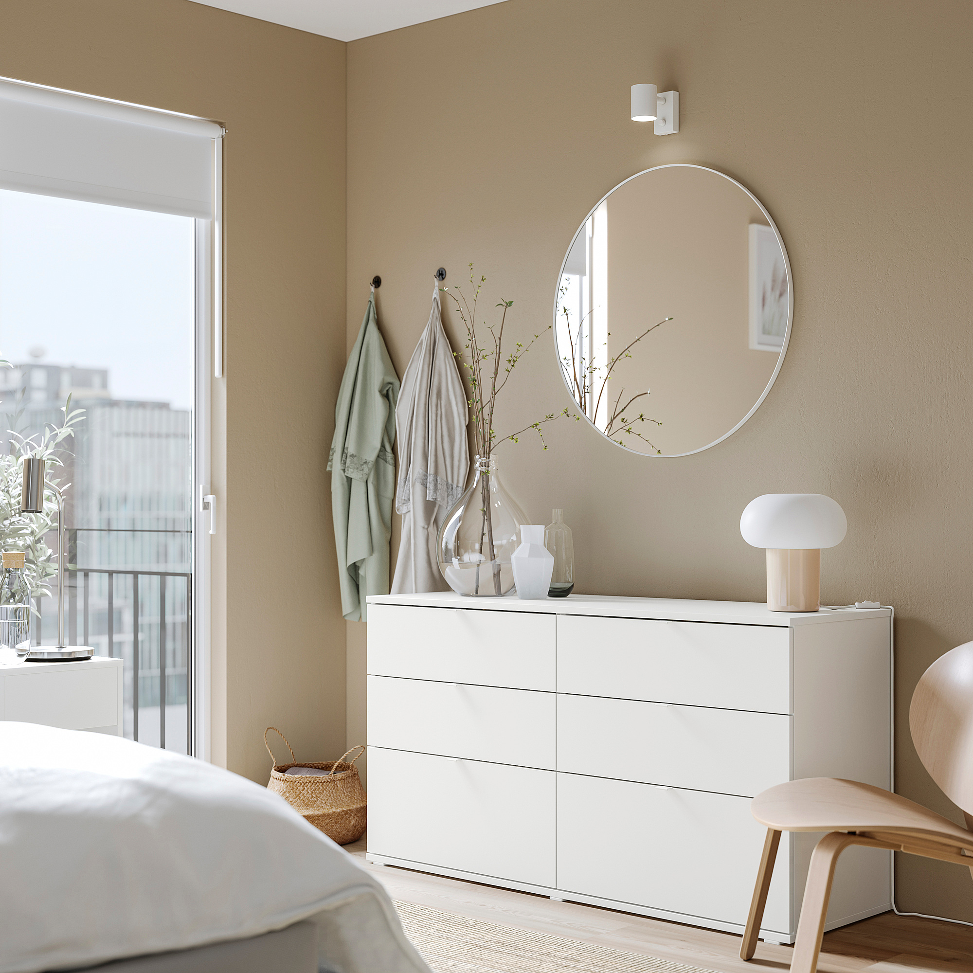 A minimalist bedroom with a white VIHALS chest of drawers. It six drawers, a round mirror, and light-colored decor.