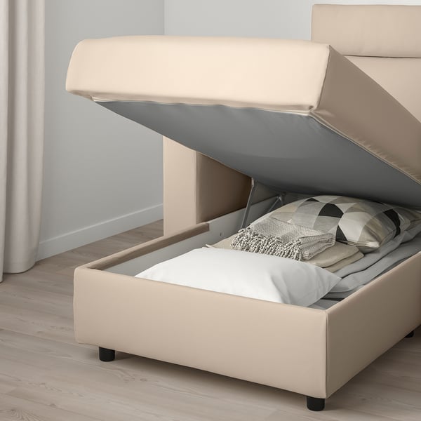 Sofa with open storage compartment, blankets, and pillow inside.