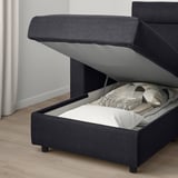 Dark grey VIMLE sofa with open storage compartment, neatly folded bed linens inside.
