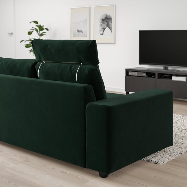 Modern green VIMLE sofa, plush velvet, wide & cushioned, with headrests, against white wall, large tv nearby.