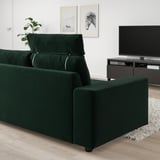 Modern green VIMLE sofa, plush velvet, wide & cushioned, with headrests, against white wall, large tv nearby.