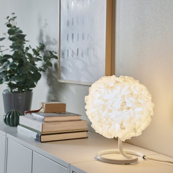 White eco-friendly VINDKAST lamp beside books, small, round, modern design.