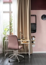 Home office setup with VITTSJÖ glass & metal desk, pink chair, plants, and clock.