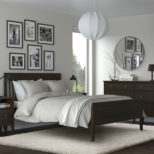 Modern bedroom with shaggy rug, dark furniture, black & white decor, hanging light, mirror, gallery wall.