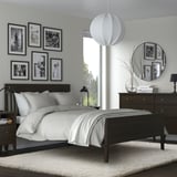 Modern bedroom with shaggy rug, dark furniture, black & white decor, hanging light, mirror, gallery wall.
