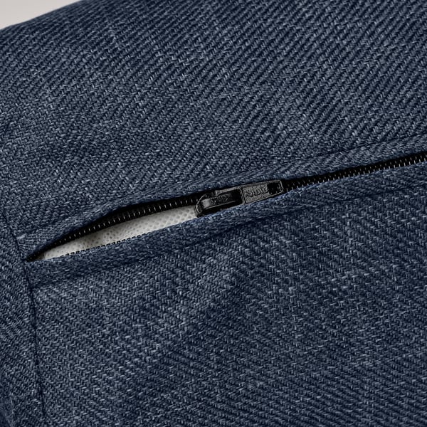 Dark blue textured fabric sofa with a smooth black zipper partially opened, revealing inner lining.