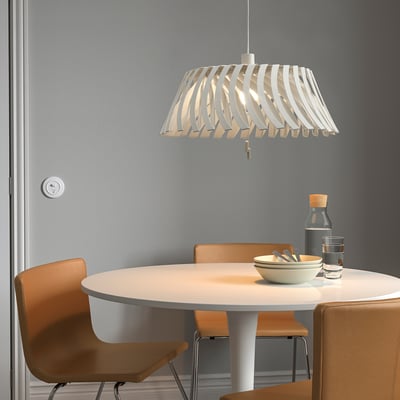 Pendant lamp YTLÄGE white, adjustable design, hangs over small dining table with chairs.