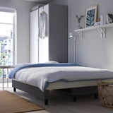 Chambre moderne avec draps bleus, cadres et lumière naturelle.