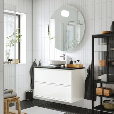 Configuration moderne de la salle de bain blanche. Lavabo ÄNGSJÖN, lavabo rond, design minimaliste, mural, grand miroir, accents noirs et décor en bois.