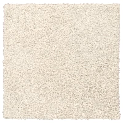 Un tapis blanc, doux et carré à la texture hirsute, fabriqué à partir de polypropylène et de caoutchouc synthétique pour une sensation de confort.