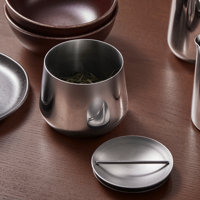 Un ensemble de cuisine en acier inoxydable : bols, théière, pot avec du thé vert sur bois. Ou, pour moins de personnages : un ensemble de cuisine en acier inoxydable avec un pot à thé sur bois.